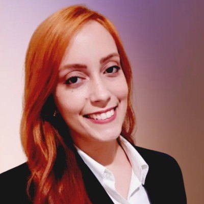 Retrato de Kalina Mendes, sorrindo, de camisa branca e blazer preto.